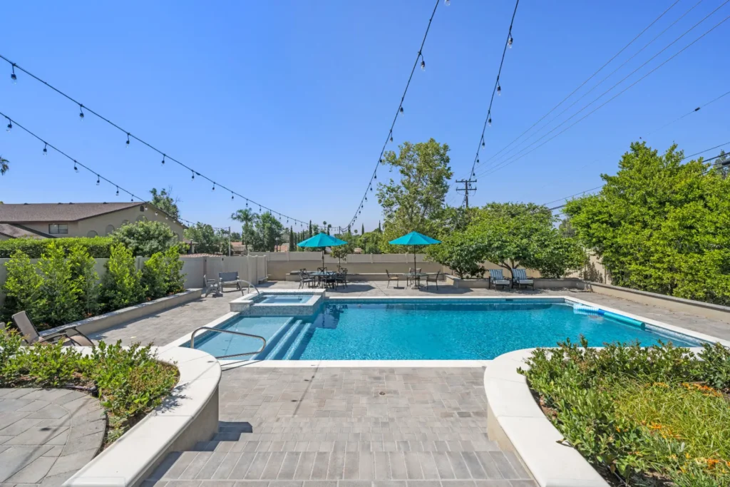 Backyard swimming pool with patio umbrellas and string lights