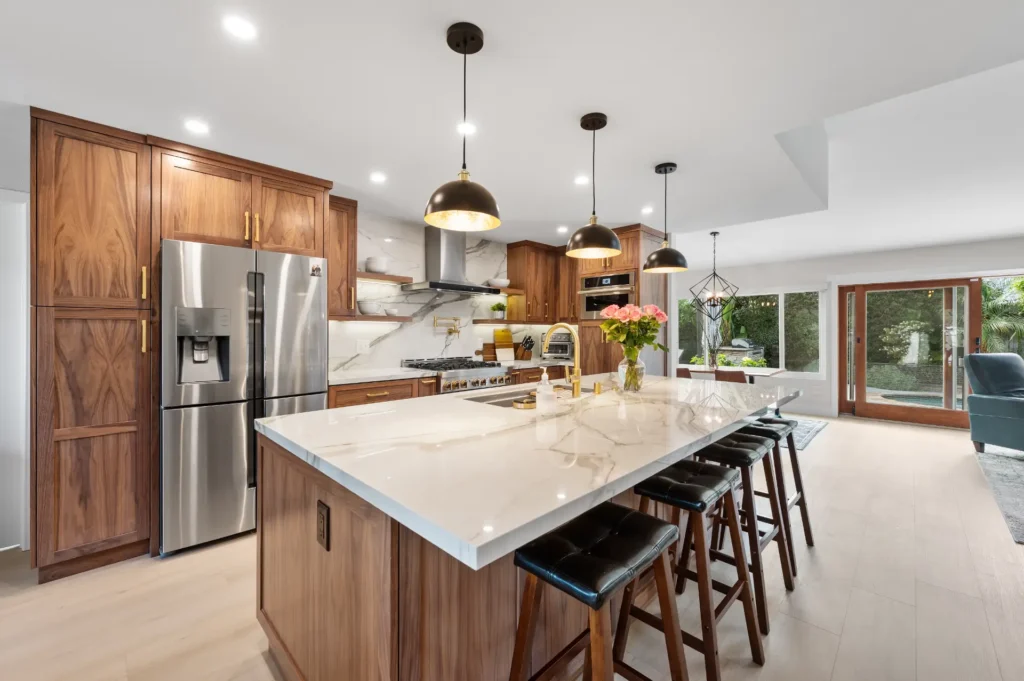 Kitchen with walnut cabinetry, a marble waterfall island and a stainless refrigerator