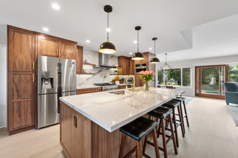 Kitchen with walnut cabinetry, a marble waterfall island and a stainless refrigerator