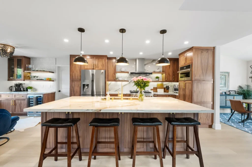 Kitchen with walnut cabinetry, a long marble island with barstools and open shelving