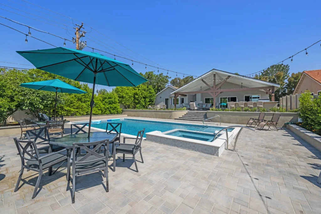Swimming pool with patio umbrellas and an outdoor dining set