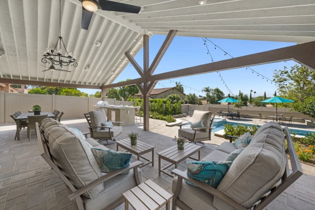 Covered patio with outdoor lounge seating beside a swimming pool