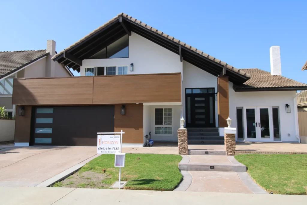 Modern farmhouse exterior with a wood accent wall and dark garage doors