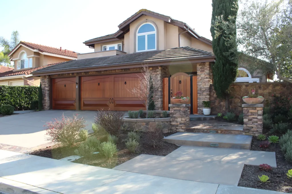 Home exterior with a wood garage door, stone veneer and mature landscaping