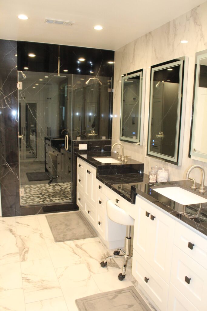 Bathroom double vanity with dark granite counters and framed mirrors